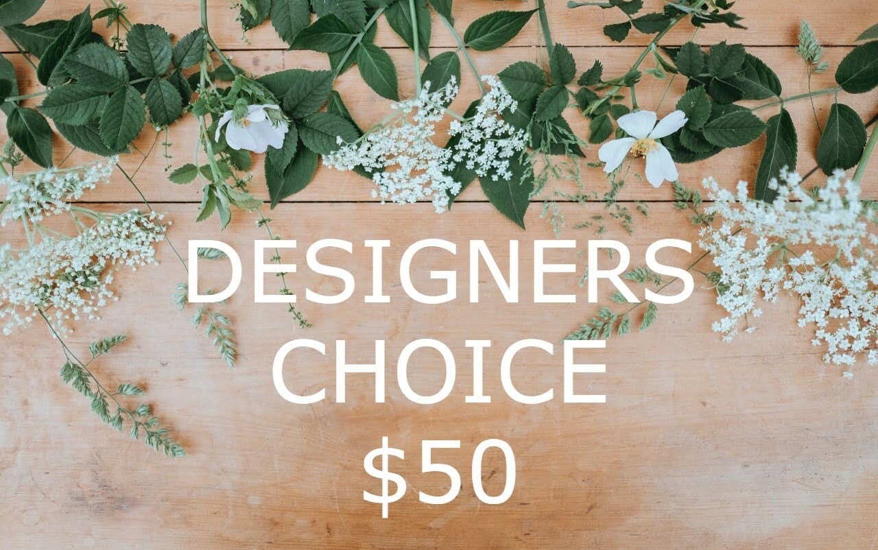 Floral-themed image with ‘DESIGNERS CHOICE $50’ text on a wooden background adorned with leaves and white blooms.