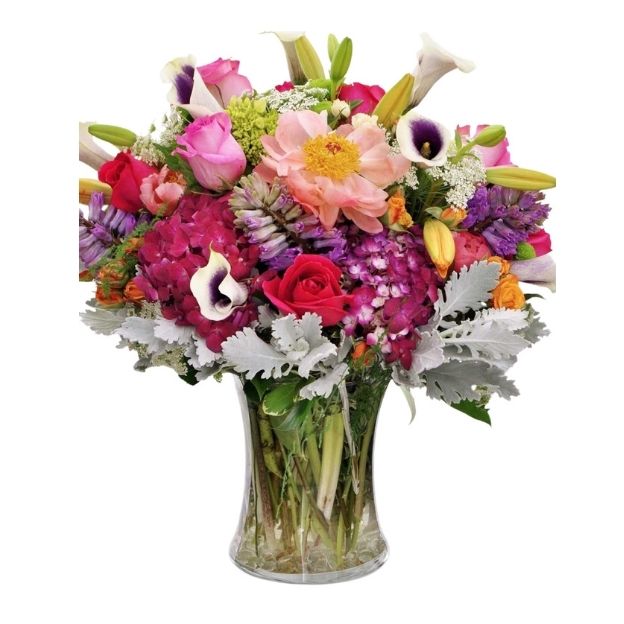 A vibrant bouquet of mixed flowers, including roses, lilies, and hydrangeas, arranged in a clear glass vase.