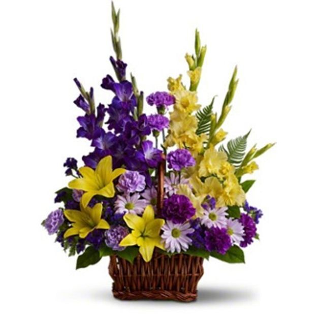 Basket arrangement with yellow lilies, purple gladiolus, and mixed daisies in bright purple and lavender tones.
